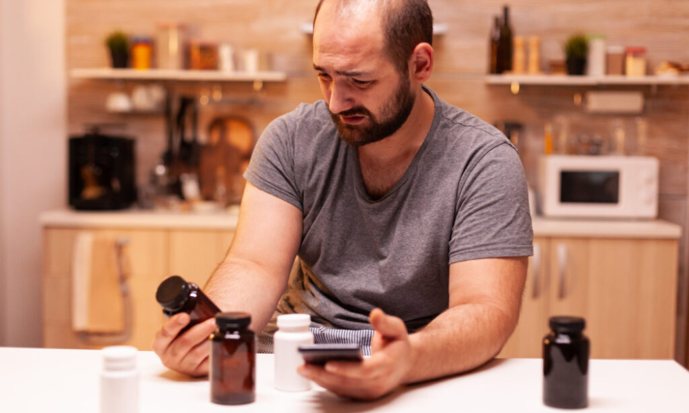 man with headache holding pills bottle sitting kitchen stressed tired unhappy worried person suffering migraine depression disease anxiety feeling exhausted with dizziness symptoms 1024x683 1