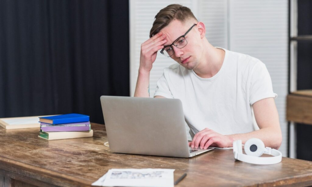 worried young man looking laptop wooden table 1 1024x684 1