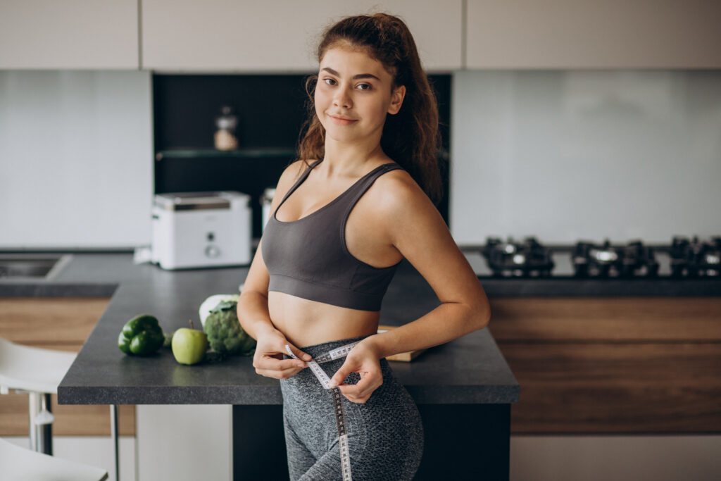 young woman with measuting tape weist kitchen