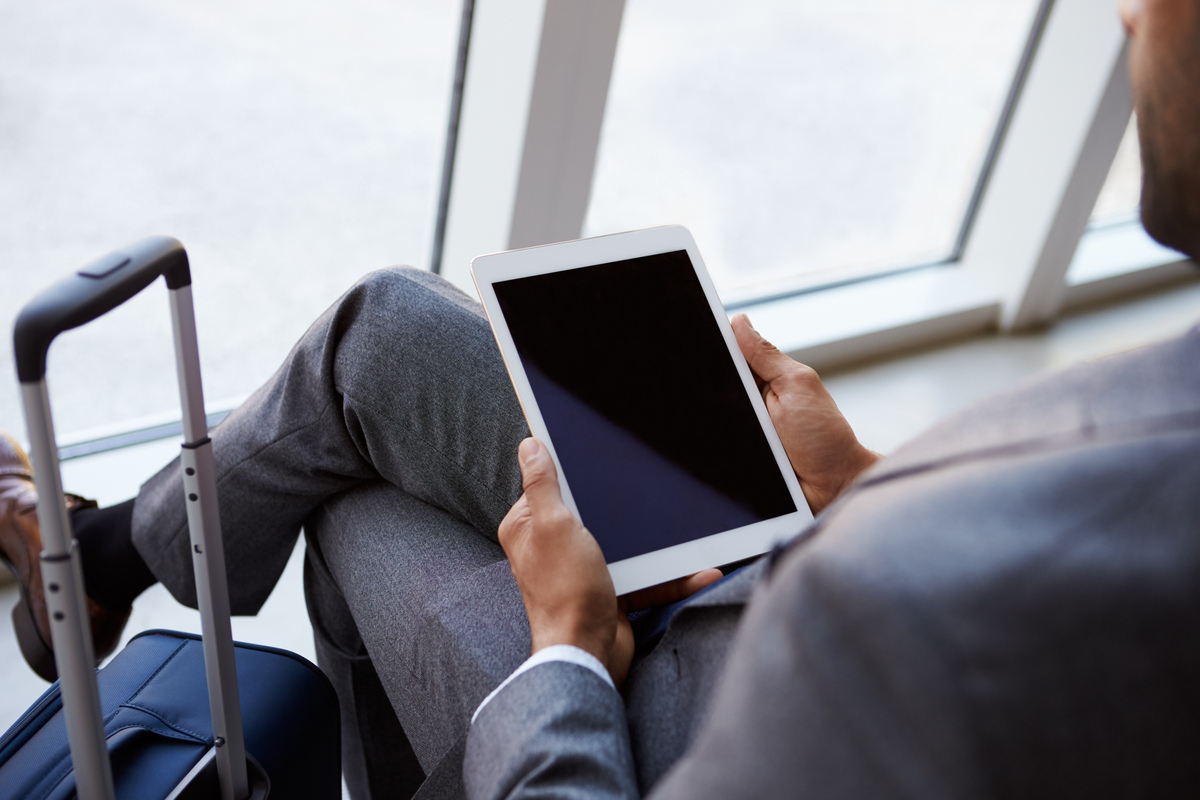 Man reviewing travel plans at the airport, illustrating what to know about traveling with testosterone