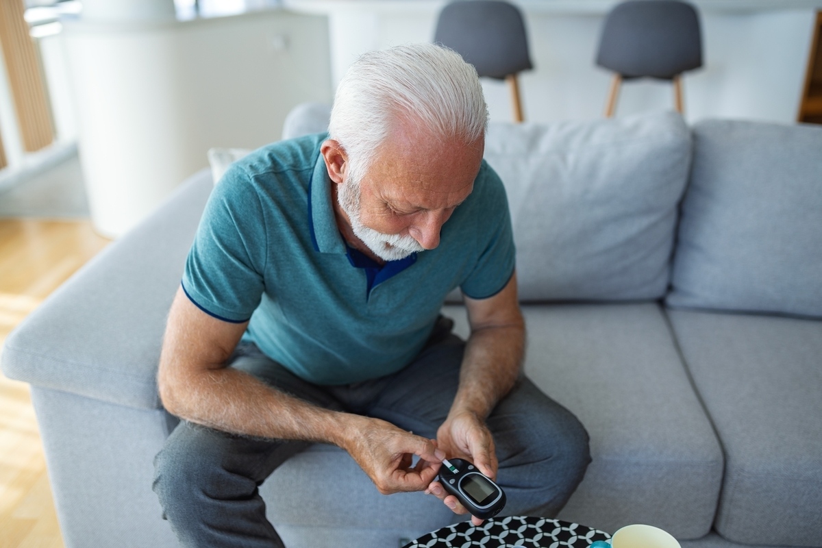 Man checking his blood sugar at home, part of the metabolic monitoring discussed in TRT and cholesterol research