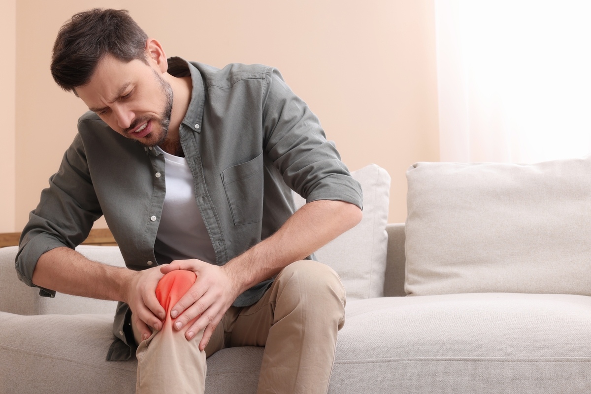 Man holding his knee in pain, illustrating the joint discomfort discussed in TRT and joint pain research